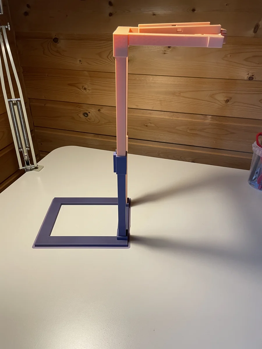 The finished 3D-printed recording stand viewed from the side, showing its base, twin masts, overhead boom, and phone cradle